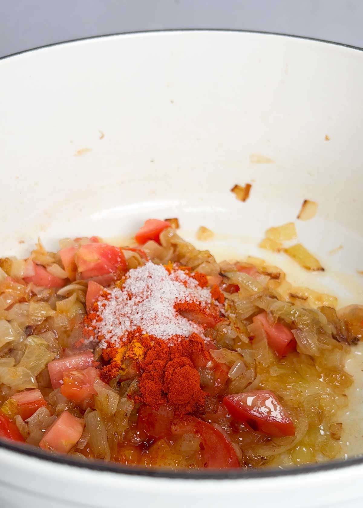 spices added into a pot of caramelised onions and tomato