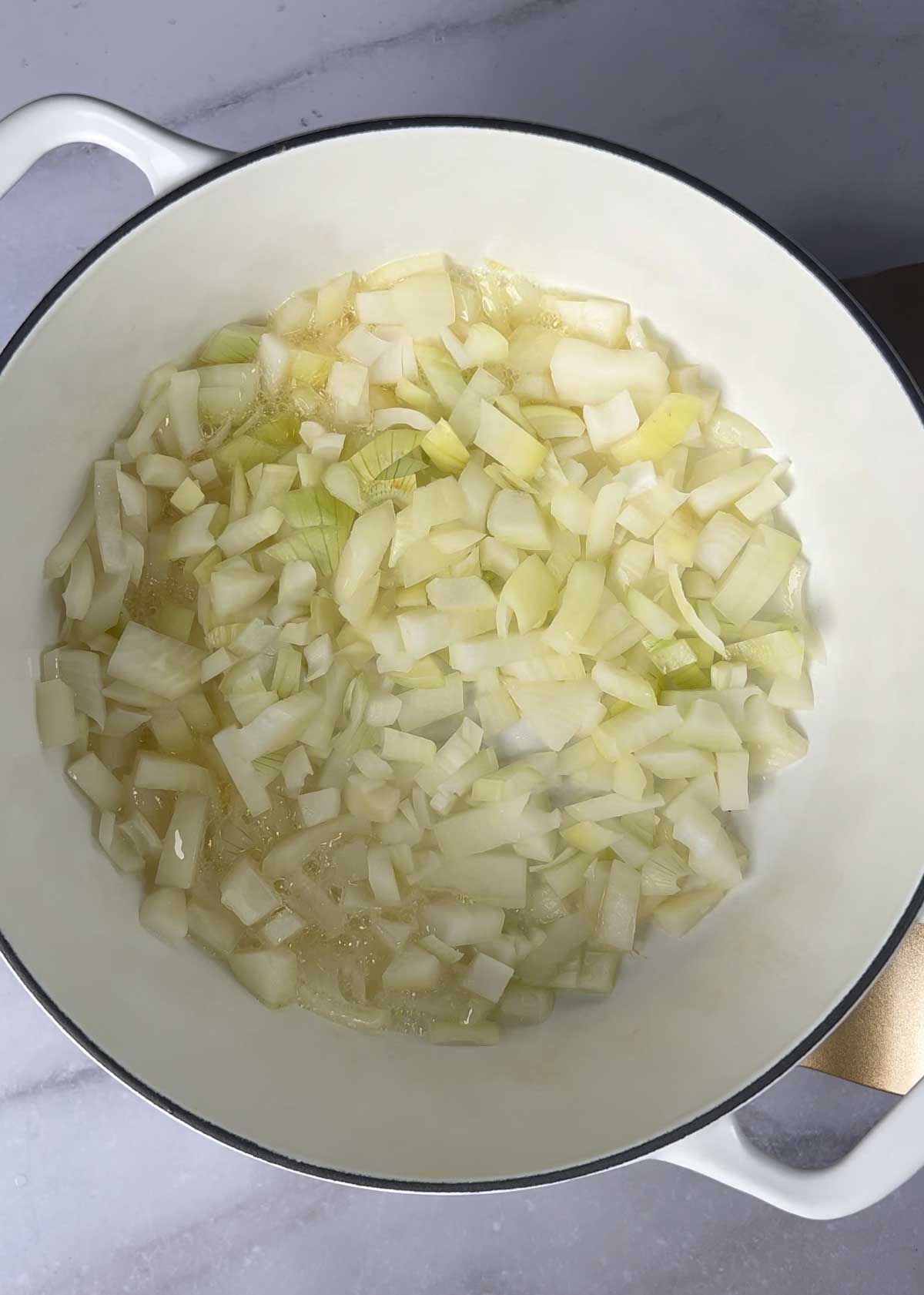 chopped onions in white cast iron dutch oven