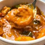 Kerala Prawn Curry with in a bowl, with one prawn being lifted in a spoon