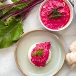 beetroot pachadi poured over rice on a plate and another bowl beside it with the beetroot pachadi in it