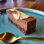a slice of healthy chocolate mousse bar on a aqua plate with a gold spoon in front of it