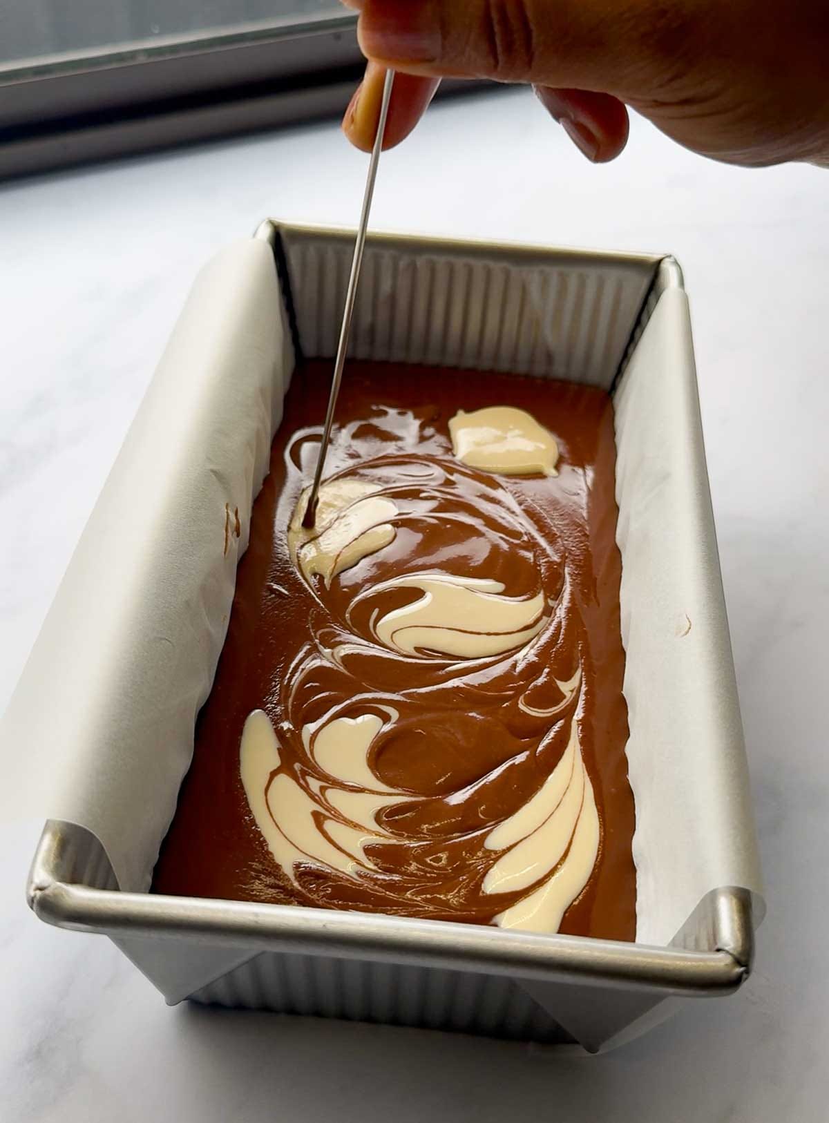 Swirling tahini into vegan chocolate mousse topping to create marble effect for healthy chocolate mousse bars.