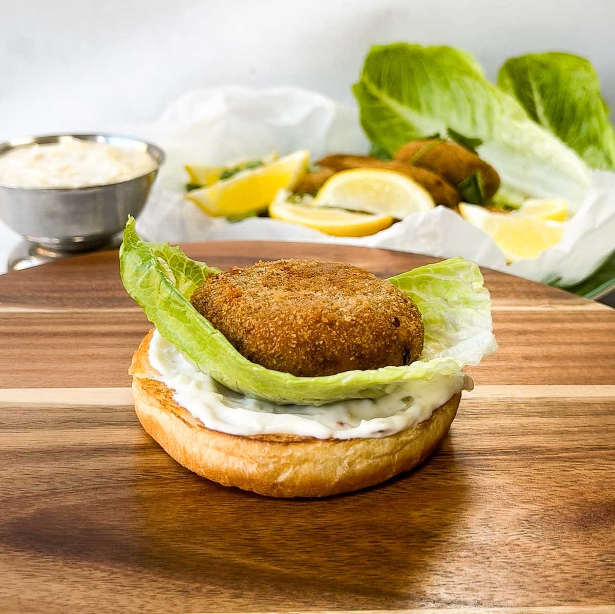 Kerala tuna fish cutlet patty served in a burger bun with lettuce and tartare sauce.