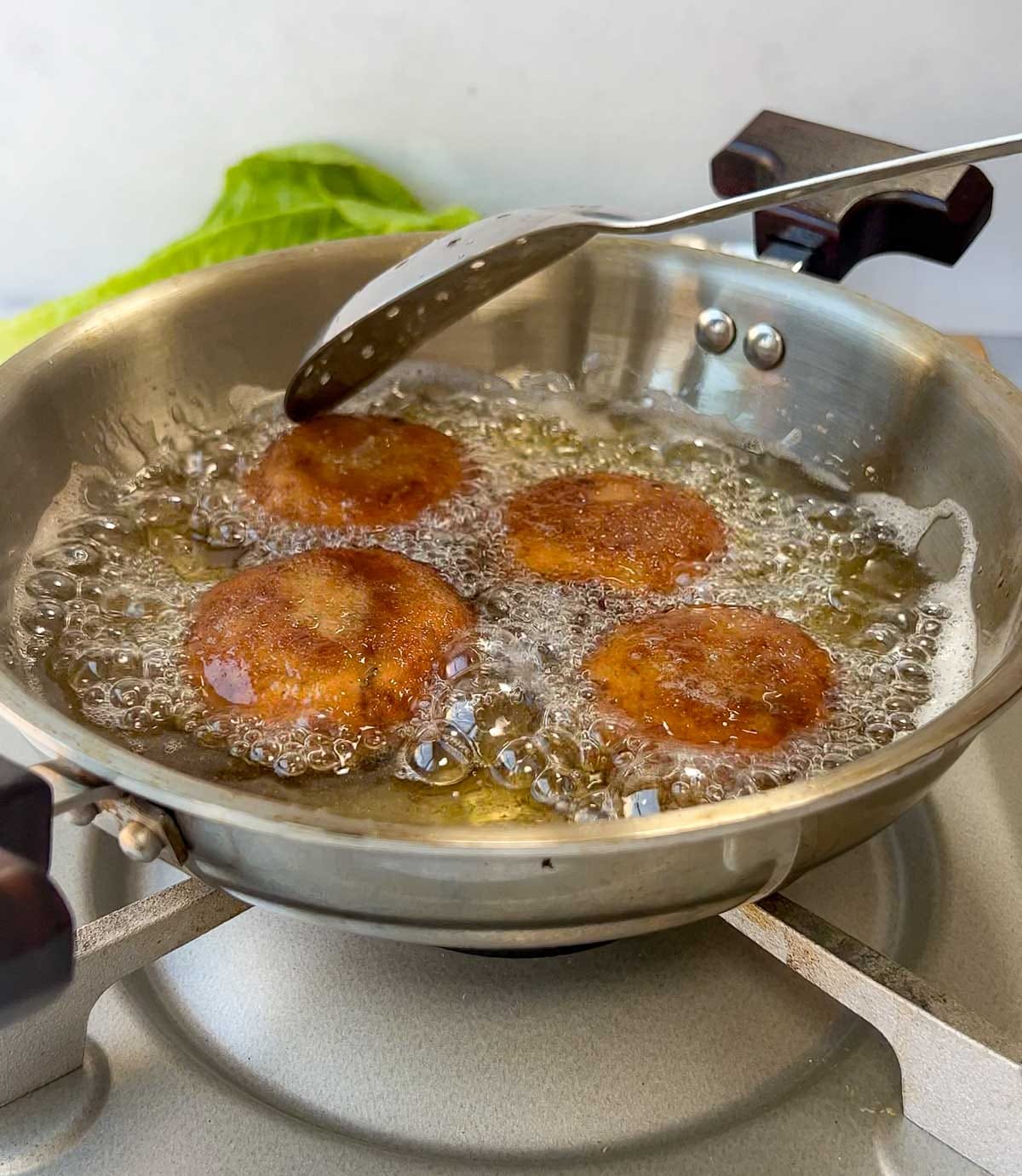 Tuna fish cutlets being deep fried in oil until golden brown and crispy.