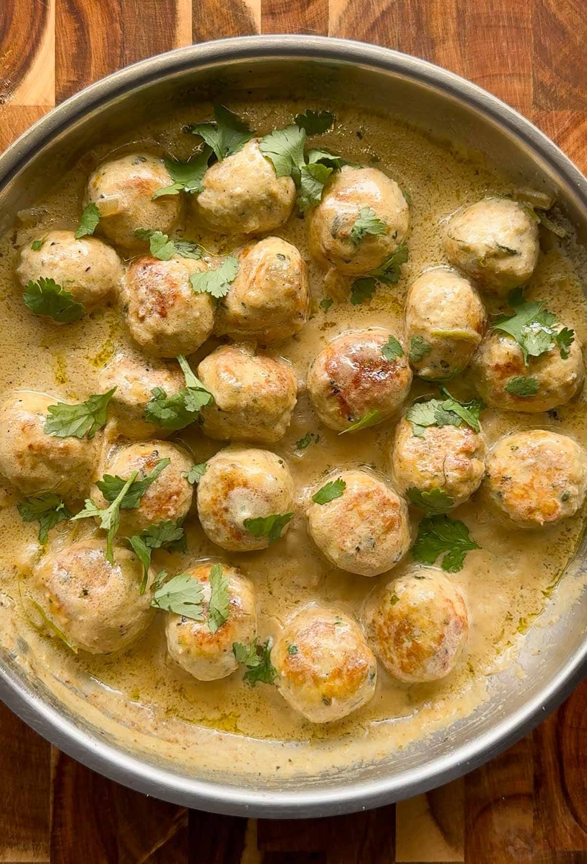 creamy chicken kofta curry in a pan, with wooden background