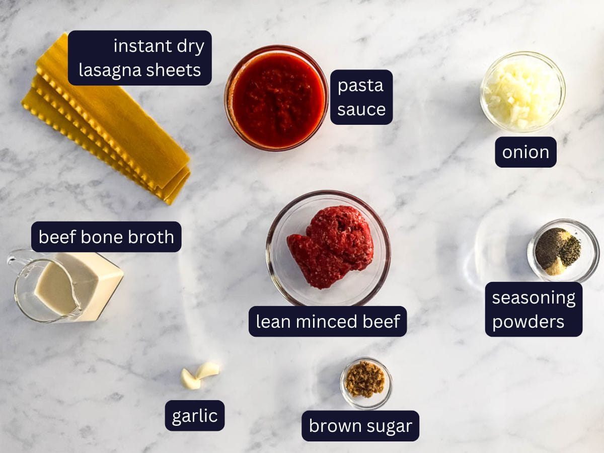 30 minute high protein skillet lasagna, meat sauce ingredients from the top view, including instant dry lasagna sheets, pasta sauce, onion, beef bone broth, lean minced beef, seasoning powders, garlic and brown sugar.