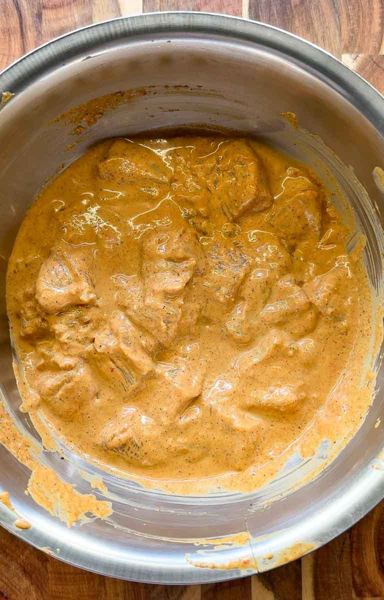 marinated chicken in a steel bowl. for satay chicken skewers.